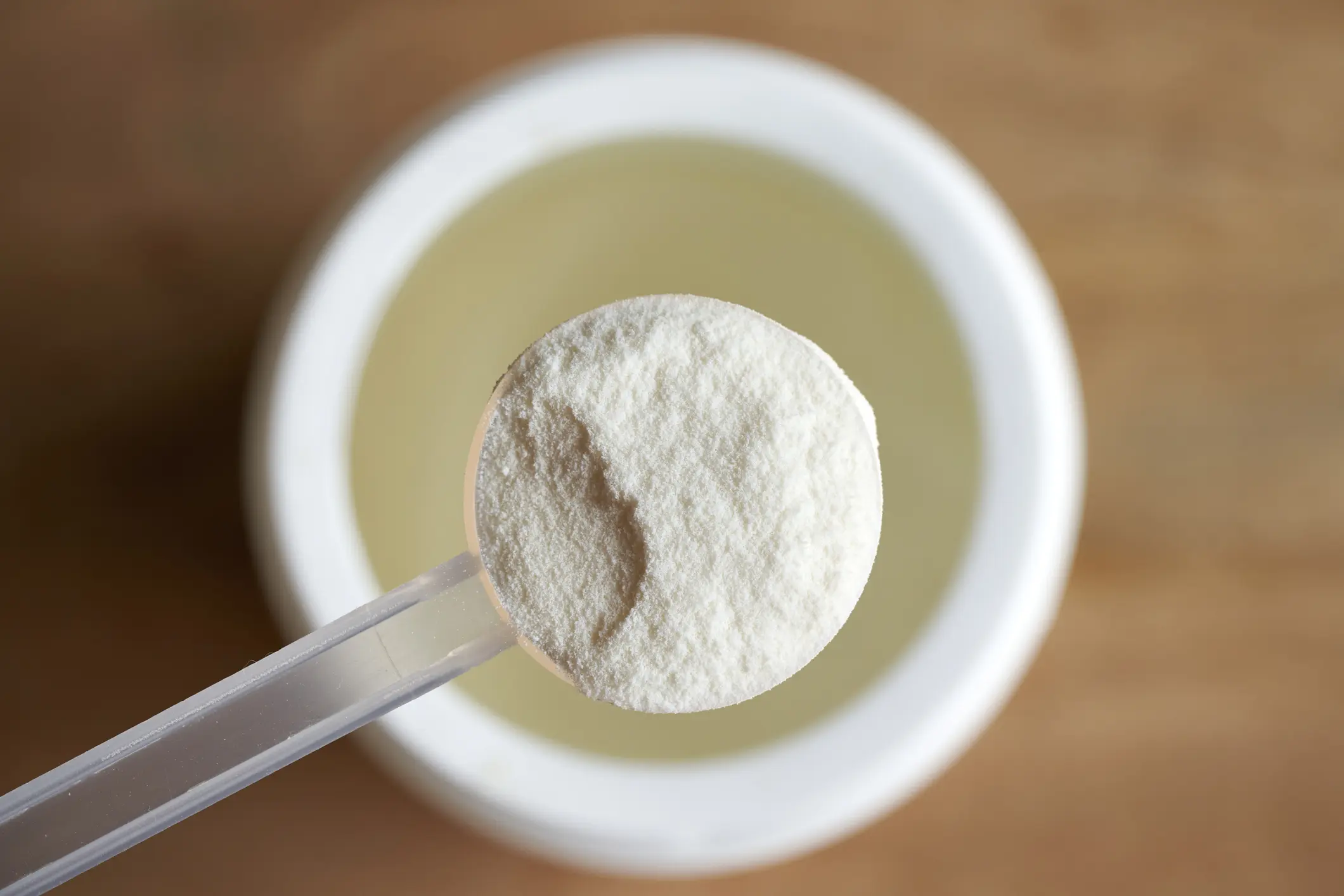 Scoop of protein powder over container.
